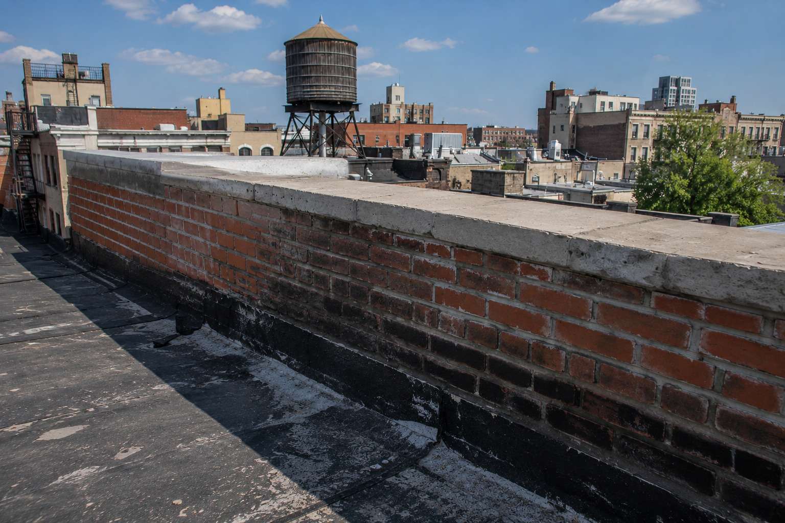 Brick parapet wall with worn coping and flashing on a flat roof